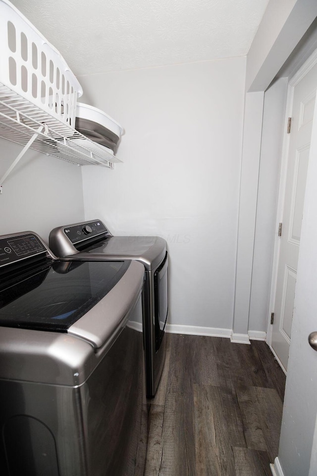 laundry area featuring baseboards, laundry area, dark wood-style floors, and washer and clothes dryer
