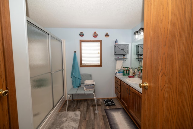 bathroom featuring vanity, a textured ceiling, wood finished floors, and a shower stall