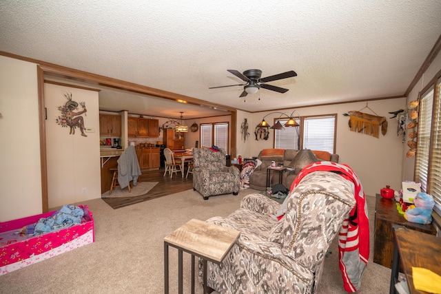 living room with crown molding, a ceiling fan, a textured ceiling, and light carpet