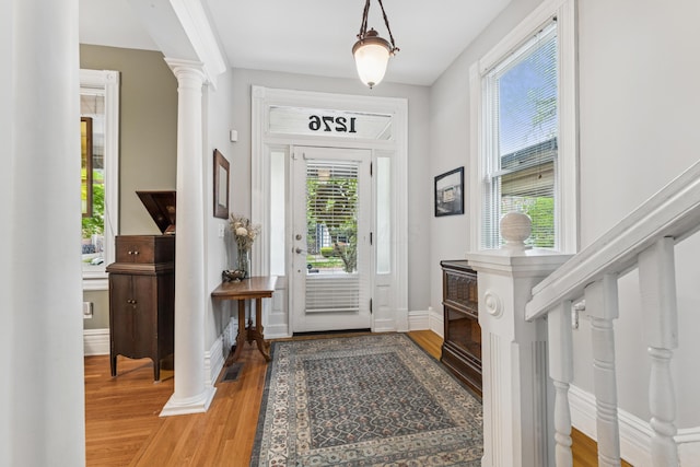 entryway with baseboards, ornate columns, and light wood-style flooring