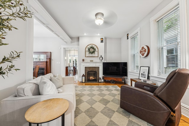 living area with recessed lighting, ceiling fan, a lit fireplace, and light wood-type flooring