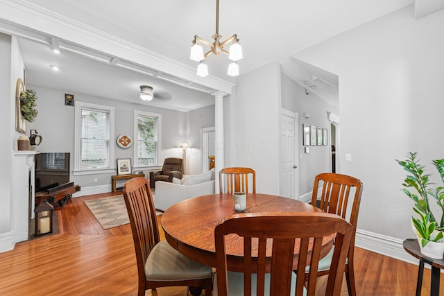 dining room featuring baseboards, light wood finished floors, a chandelier, and decorative columns
