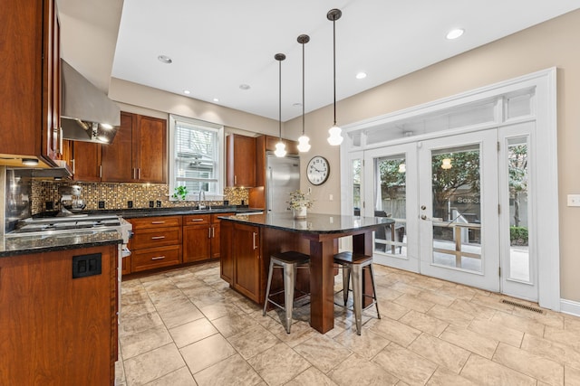 kitchen with a sink, a kitchen breakfast bar, a center island, decorative backsplash, and built in refrigerator