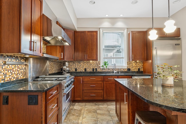 kitchen featuring a sink, high end appliances, decorative backsplash, and wall chimney exhaust hood