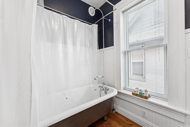 bathroom with a shower with curtain, a freestanding tub, wainscoting, and wood finished floors