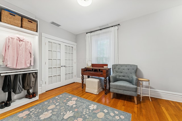 sitting room with baseboards, french doors, wood finished floors, and visible vents