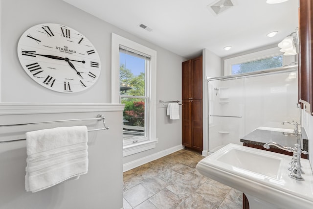 bathroom featuring a shower stall, baseboards, a wealth of natural light, and a sink