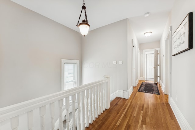 hall with baseboards, an upstairs landing, and wood finished floors