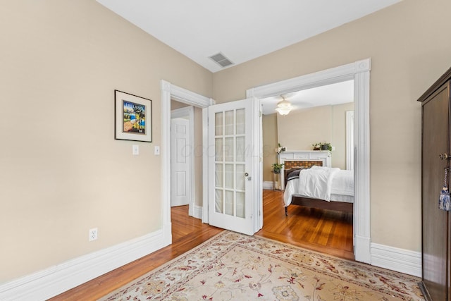 bedroom with french doors, baseboards, visible vents, and wood finished floors