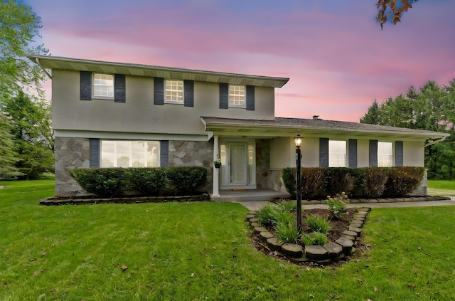 traditional-style home with stone siding, covered porch, stucco siding, and a front lawn