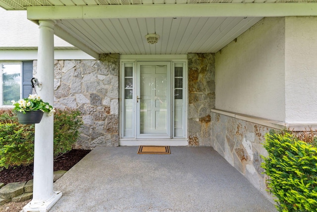 view of exterior entry with stone siding and stucco siding