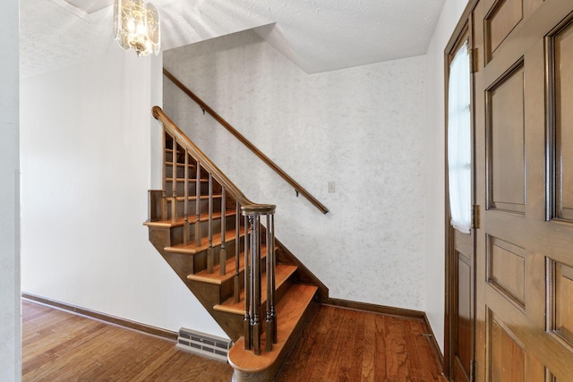 stairs featuring baseboards, a textured ceiling, and wood finished floors
