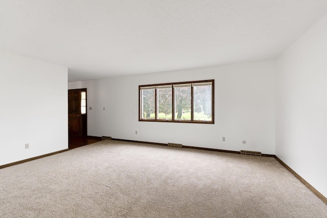 unfurnished room featuring carpet flooring, visible vents, and baseboards