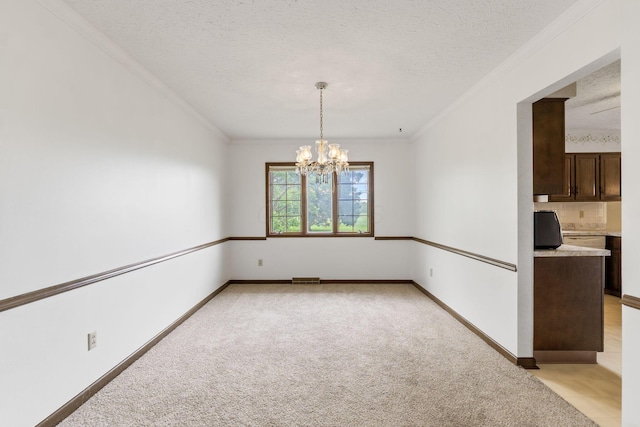 spare room with light colored carpet, a chandelier, crown molding, and a textured ceiling