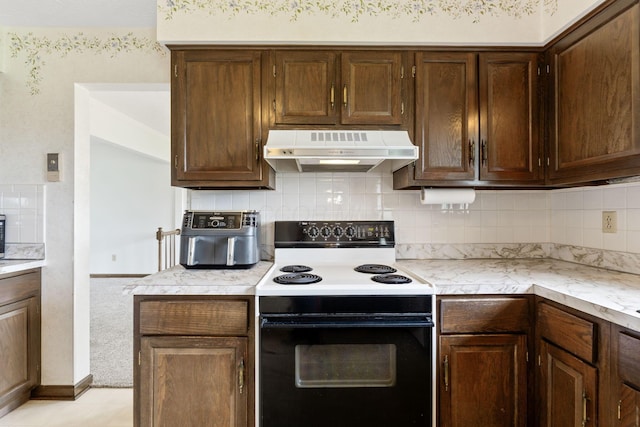 kitchen with dark brown cabinets, electric range oven, backsplash, under cabinet range hood, and light countertops