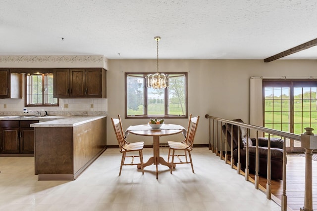 kitchen with a notable chandelier, light countertops, a textured ceiling, and dark brown cabinetry