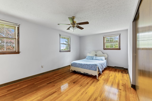 bedroom featuring multiple windows, light wood-style floors, visible vents, and a textured ceiling