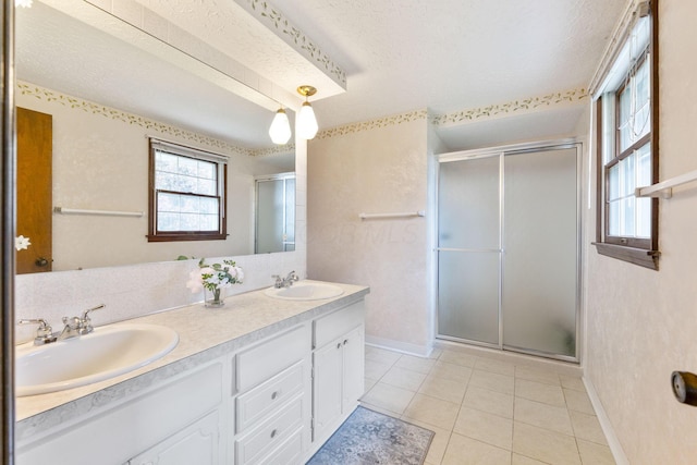 full bath featuring double vanity, baseboards, a stall shower, and a sink