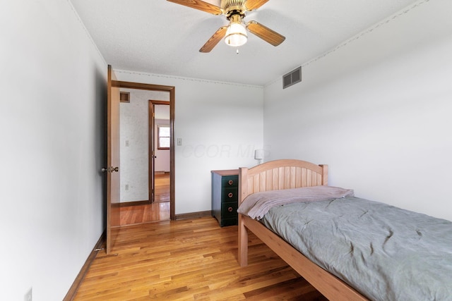 bedroom featuring baseboards, light wood-style floors, visible vents, and a ceiling fan