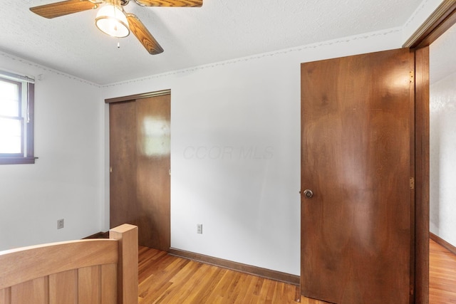 unfurnished bedroom with baseboards, light wood-style floors, ceiling fan, and a textured ceiling