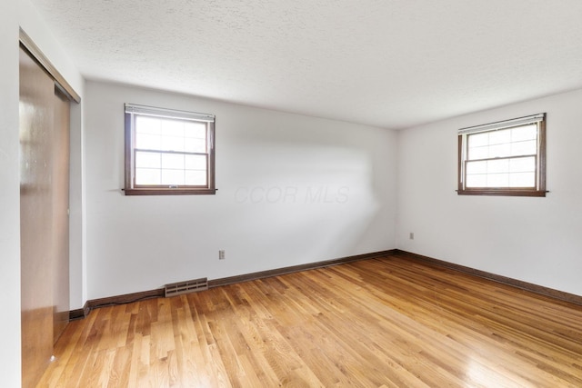 unfurnished room featuring baseboards, light wood-type flooring, and visible vents