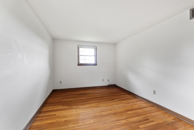 unfurnished room featuring light wood-type flooring, visible vents, and baseboards