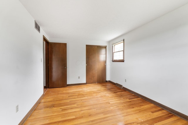 unfurnished room featuring light wood-type flooring, baseboards, and visible vents