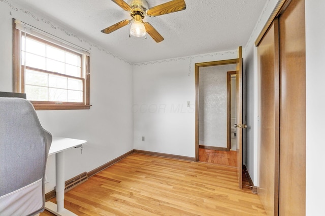 unfurnished bedroom featuring light wood-style flooring, a textured ceiling, baseboards, and a closet