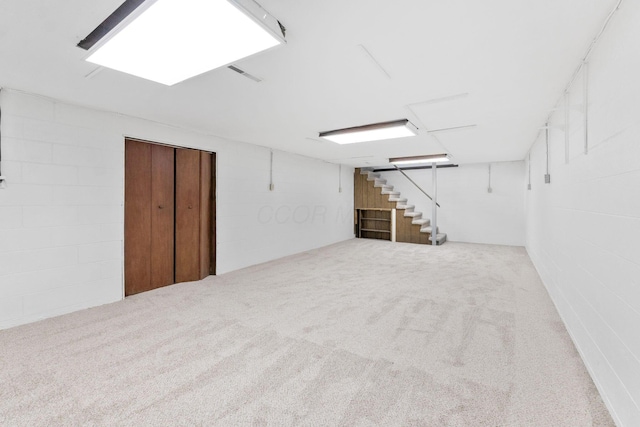 finished below grade area with stairway, carpet floors, and concrete block wall