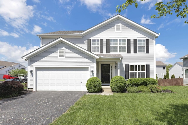 traditional-style house featuring fence, an attached garage, driveway, and a front yard