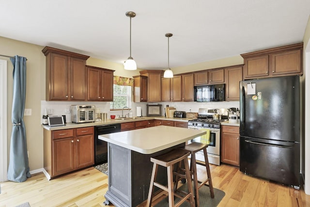 kitchen featuring a sink, light countertops, light wood-style flooring, tasteful backsplash, and black appliances
