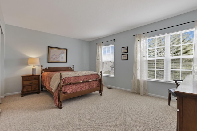 bedroom featuring baseboards, visible vents, and light colored carpet