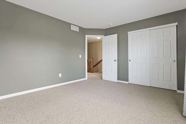 unfurnished bedroom with visible vents, carpet, baseboards, and a closet