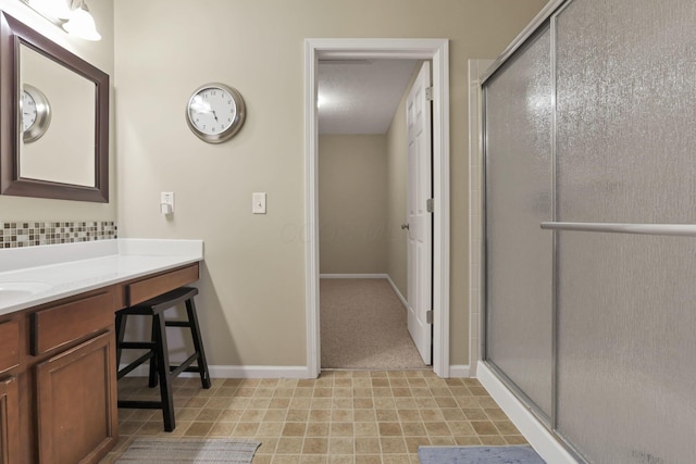 full bath featuring vanity, baseboards, decorative backsplash, and a shower stall