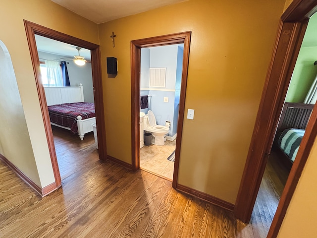corridor with baseboards, wood finished floors, and visible vents