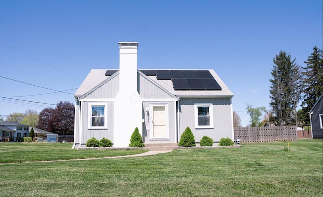 modern farmhouse with a chimney, a front yard, and solar panels