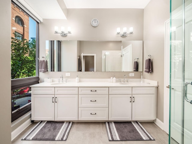 full bathroom featuring a sink, a stall shower, double vanity, and a wealth of natural light