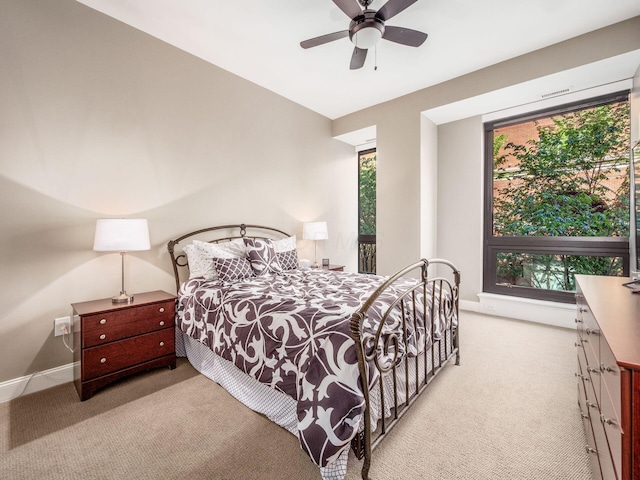 bedroom featuring light colored carpet, a ceiling fan, and baseboards