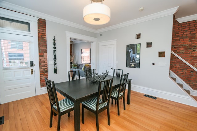 200 Thurman Ave, Columbus, OH 43206 - dining room featuring crown molding, brick wall, baseboards, light wood-type flooring, and stairway