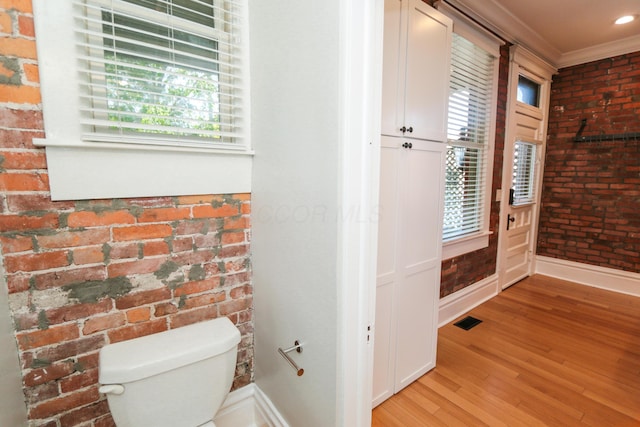 200 Thurman Ave, Columbus, OH 43206 - bathroom featuring baseboards, wood finished floors, brick wall, and visible vents