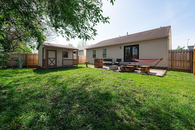 back of property with a fenced backyard, a patio area, a storage shed, an outdoor fire pit, and a yard