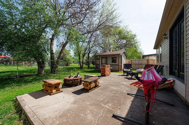view of patio featuring a fenced backyard, a storage unit, an outdoor structure, and an outdoor fire pit