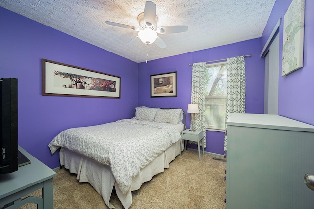 bedroom with baseboards, ceiling fan, carpet, and a textured ceiling
