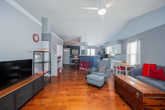 living area featuring a textured ceiling, ceiling fan, wood finished floors, and vaulted ceiling
