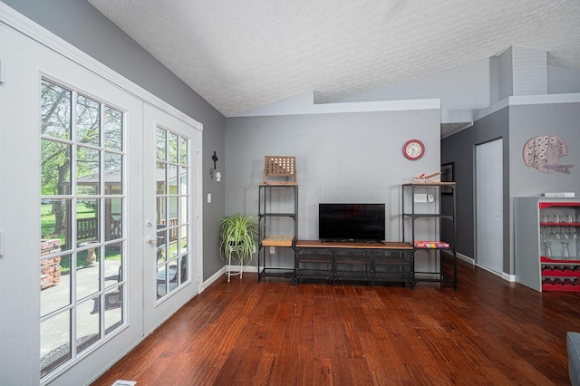 living area with baseboards, a textured ceiling, wood finished floors, and vaulted ceiling