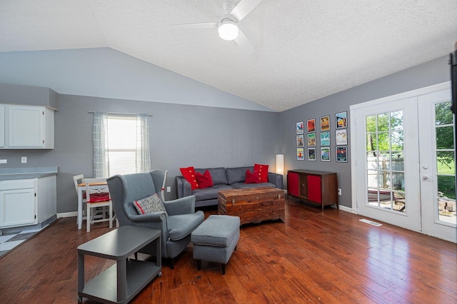 living room with ceiling fan, a textured ceiling, lofted ceiling, visible vents, and dark wood-style floors