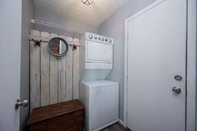 washroom with laundry area, a textured ceiling, stacked washer / drying machine, and wood finished floors