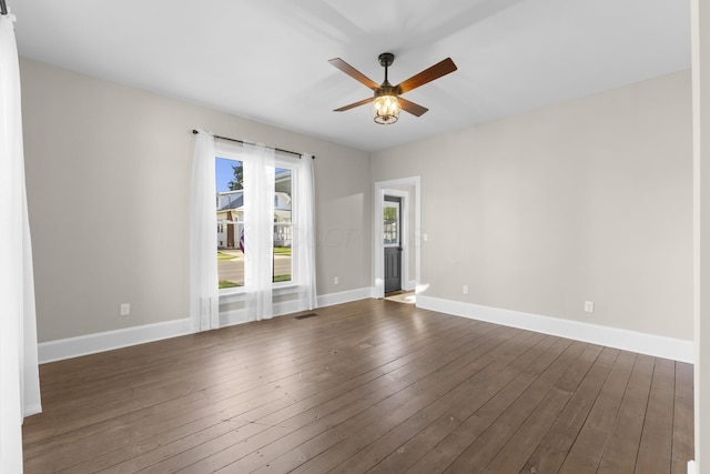 spare room featuring baseboards, ceiling fan, visible vents, and dark wood-type flooring