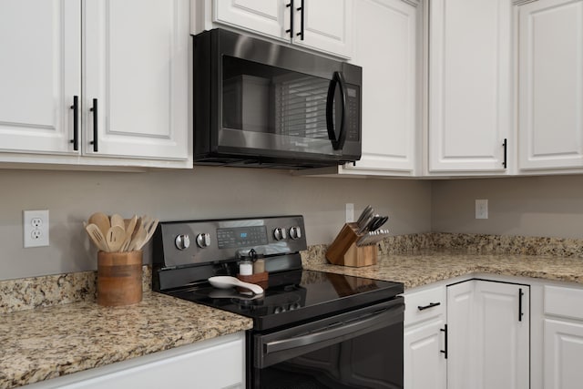 kitchen with black range with electric cooktop, white cabinets, and light stone countertops