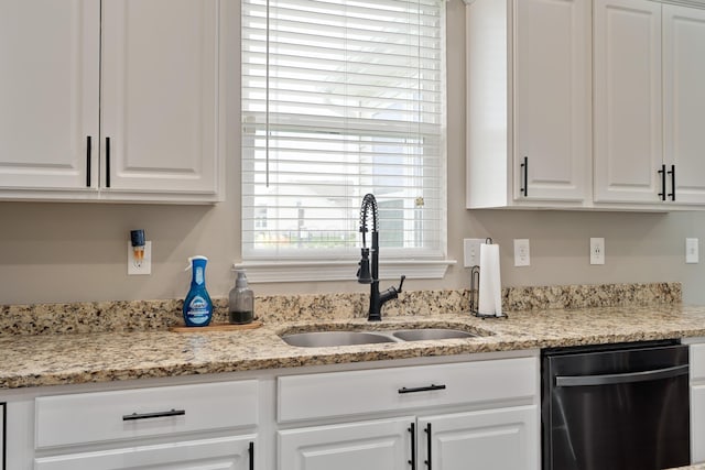 kitchen with light stone counters, a sink, white cabinetry, and dishwasher